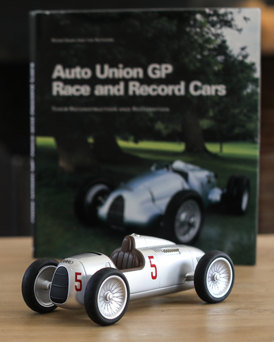 Baghera AUDI-licensed Racing Toy Car in front of Poster on table